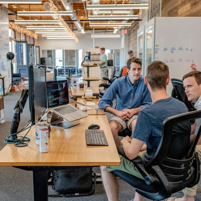 Developers talking at a desk with a computer