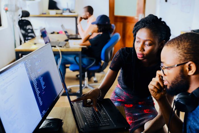 Two people collaborating on code at a desktop computer